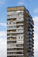 High-rise apartment building with aged concrete facade and enclosed balconies, reflecting...