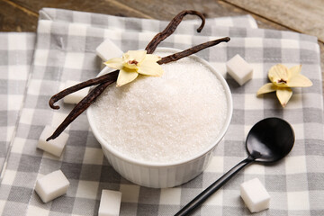 Bowl of vanilla sugar with pods and flowers on wooden background, closeup