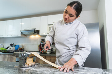 Professional chef making fresh pasta with a traditional machine in a modern kitchen