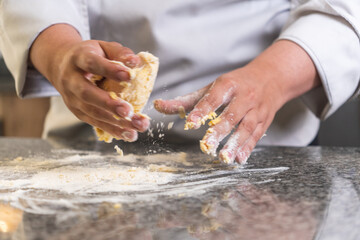 Chef kneading dough on marble countertop in restaurant kitchen