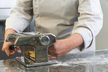 Chef making fresh pasta with a traditional pasta machine