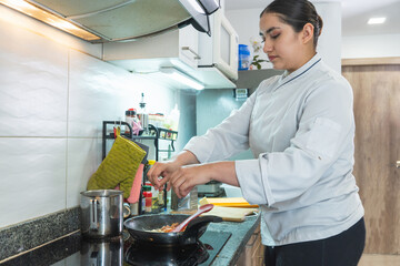 Chef adding spices to frying pan while cooking in kitchen