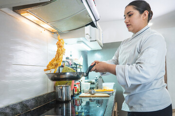 Professional chef flipping pasta in a modern kitchen