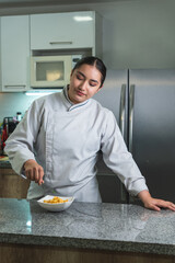 Female chef arranging pasta dish in modern kitchen
