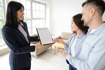 Female real estate agent with agreement and couple in room