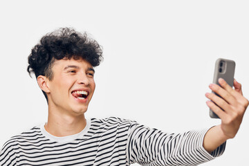 Smiling young man taking a selfie with smartphone, casual striped shirt and curly hair, bright...