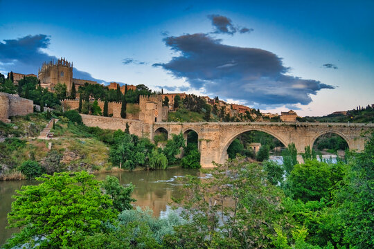 San servando castle and alc&aacute;ntara bridge spanning tagus river in toledo at sunset