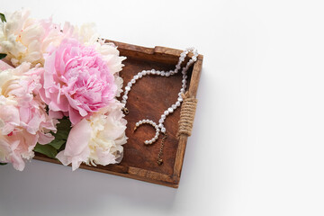 Wooden tray with beautiful peony flowers and jewellery isolated on white background, closeup