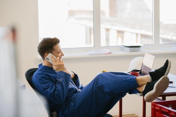 Worker relaxing with feet up on desk while talking on phone
