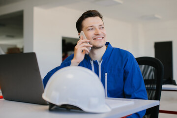 Smiling engineer talking on mobile phone at desk