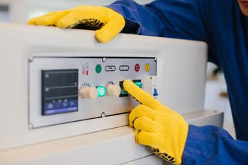Technician operating industrial machinery with control panel buttons