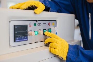 Worker operating industrial machinery with control panel buttons