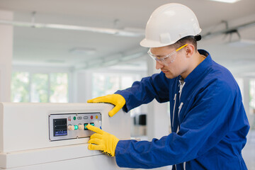 Technician operating industrial machinery pushing buttons on control panel
