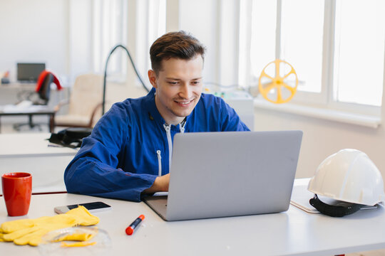 Smiling industrial worker using laptop in factory office