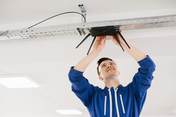 Technician installing wireless router on ceiling in office building