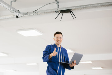 Technician installing wireless router and giving thumbs up in modern office