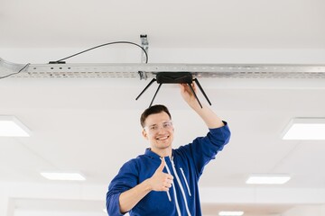 Technician installing wireless router on ceiling and giving thumbs up