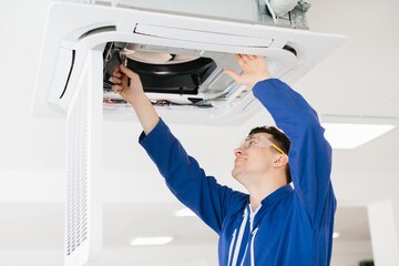 Electrician repairing air conditioning system using screwdriver