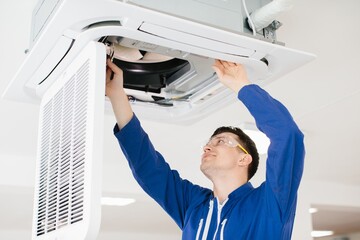 Technician repairing air conditioner unit wearing safety glasses