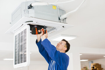 Hvac technician installing air conditioner unit using cordless drill