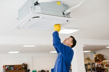Technician installing air conditioning unit in a warehouse