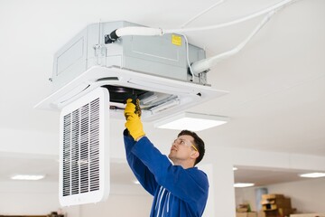 Hvac technician installing air conditioning unit on ceiling
