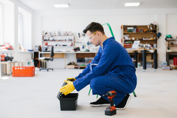 Technician opening toolbox in workshop wearing protective goggles
