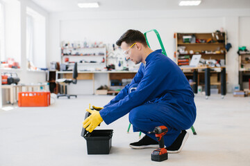 Technician opening toolbox in workshop with protective glasses and gloves