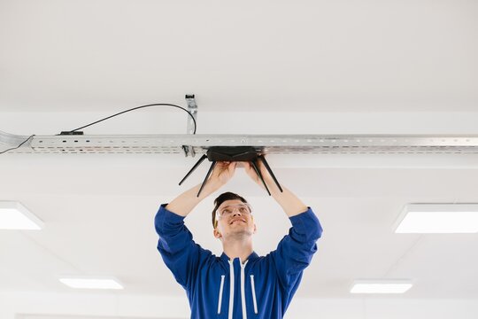 Technician installing wireless router on ceiling in office building