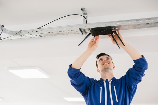 Technician installing wireless router on ceiling in office building