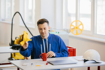 Worker removing protective gloves while drinking coffee at desk