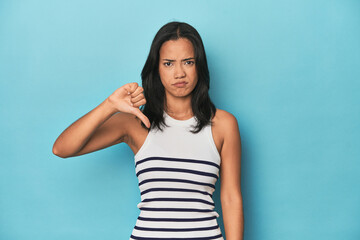 Filipina young woman on blue studio showing thumb down, disappointment concept.