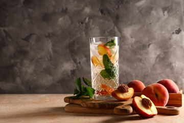 Glass of fresh peach lemonade with mint and fruits on beige table