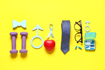Male sign, ribbon, heart, pills and male accessories on yellow background. Prostate cancer...