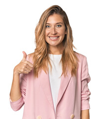 Young blonde in stylish pink suit smiling and raising thumb up