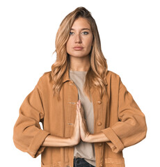 Caucasian blonde woman in studio praying, showing devotion, religious person looking for divine...