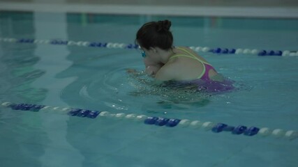 A child happily takes swimming lessons in a bright pool, focusing on water safety and learning aspects
