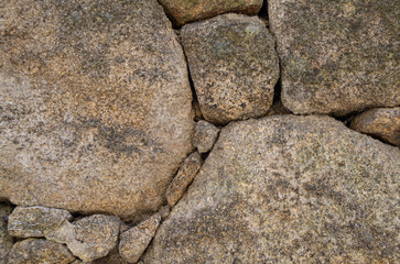 Close-up of an aged stone wall composed of irregular granite rocks, perfect for use in backgrounds,...