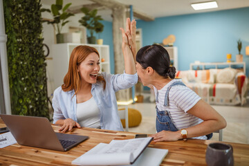 Multicultural female friends high five for support at home office