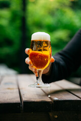 A person is holding a glass of beer with foam on top
