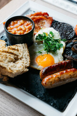 A plate of breakfast food with bacon, eggs, and sausage