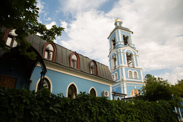 Beautiful old blue church building with clock tower in the citys street under blue summer day sky....