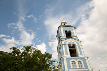Beautiful old blue church building with clock tower in the citys street under blue summer day sky....
