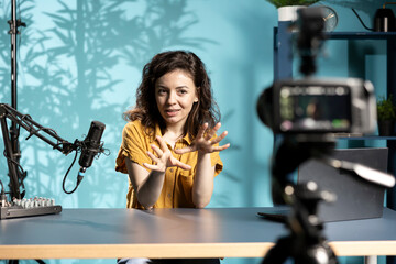Enthusiastic internet show host hitting the record button on professional camera, using microphone...