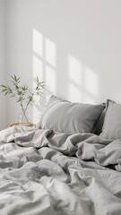 Close up of gray bedding with pillows and a small plant in a clear vase on a wooden tray