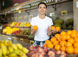 Adult woman buyer choosing fresh oranges in vegetable shop