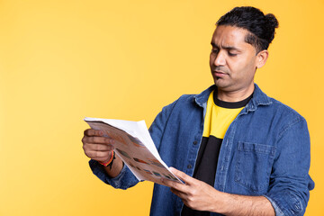 Indian accountant doing profit analysis for company and browsing files, standing against orange...