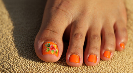 Toenails with orange nail polish and floral design