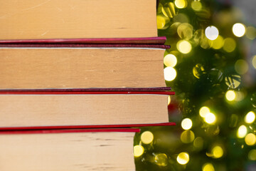 Christmas books.Stack of Books with Bokeh Background. Books with red covers stack on Christmas tree...