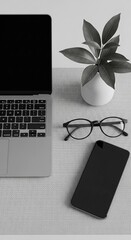 Modern workspace: A minimalist modern workspace features a laptop, glasses, phone, and a vase with greenery, offering a glimpse into a serene and productive environment.